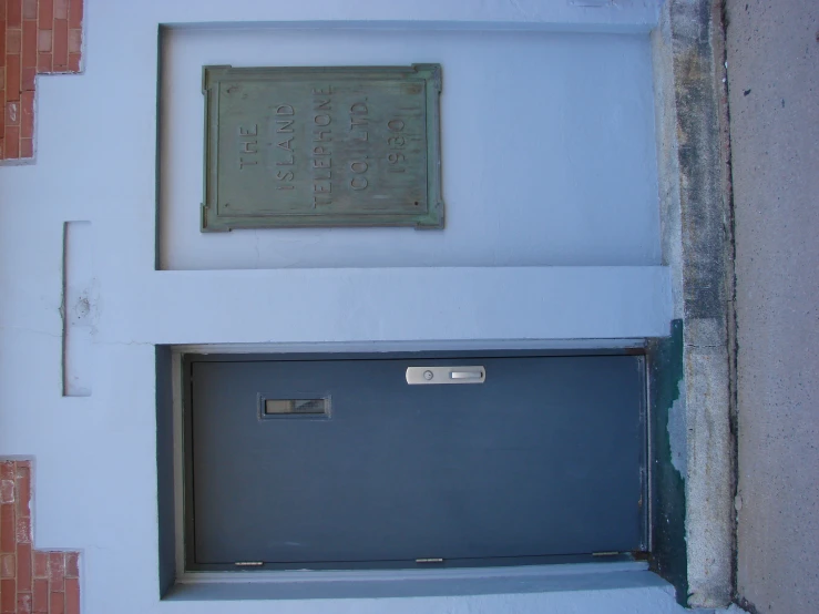 a wall with a door and small sign hanging on it