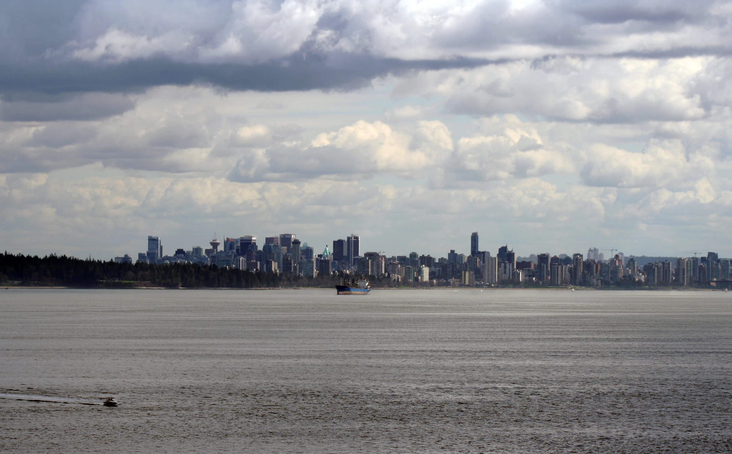 a boat sailing across a large body of water near a city