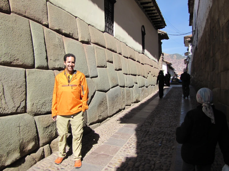 a man standing by a wall and smiling