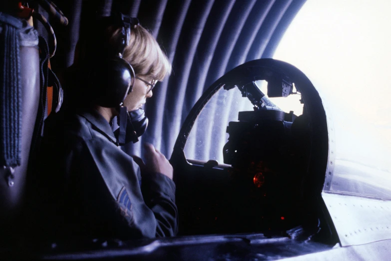 a girl talking on a cell phone sitting inside of an airplane cockpit