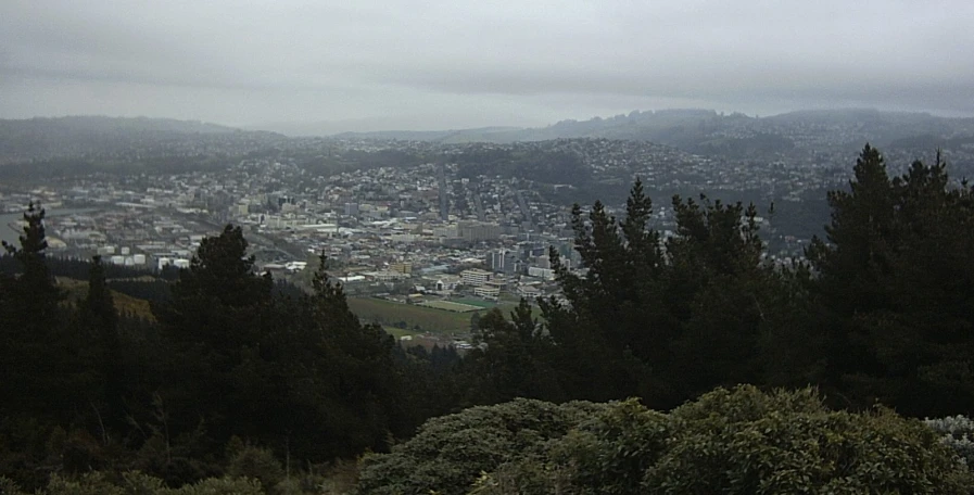 a cloudy view of a city from the top of a mountain