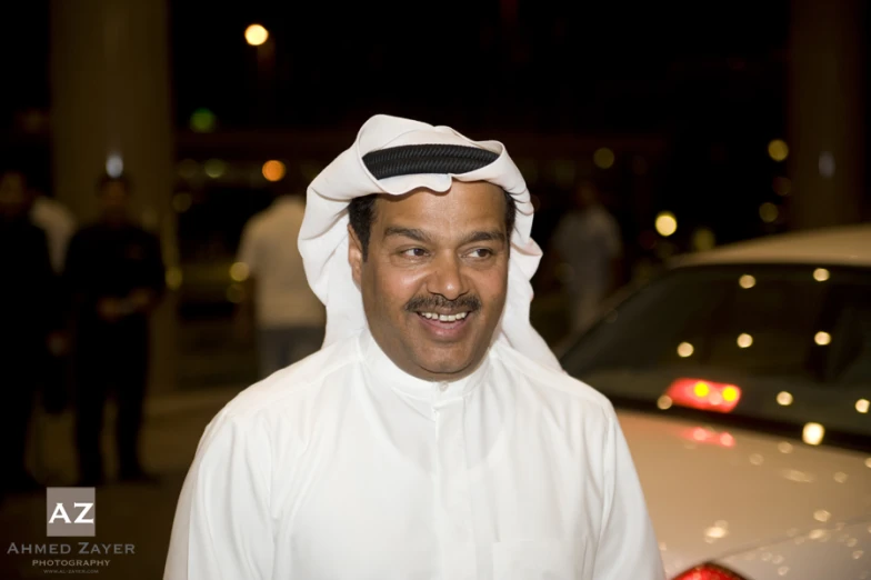 a man with a large smile on his face standing next to a car