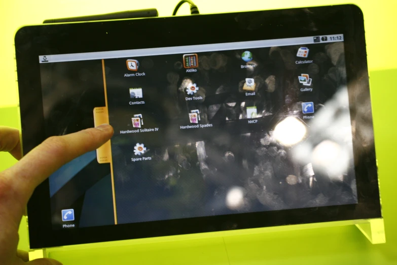 person pointing to tablet screen with other electronic items on display