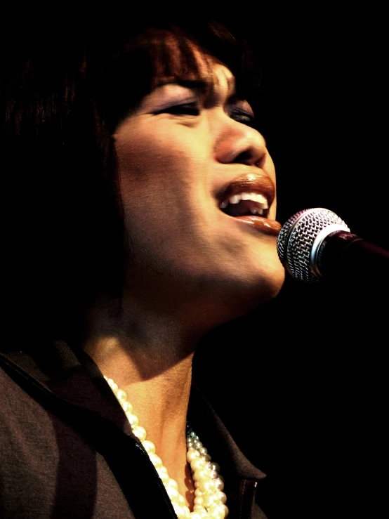 a close up of a person singing into a microphone