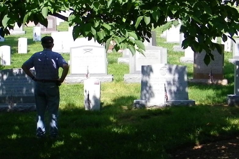 a man standing in the grass between two headstones