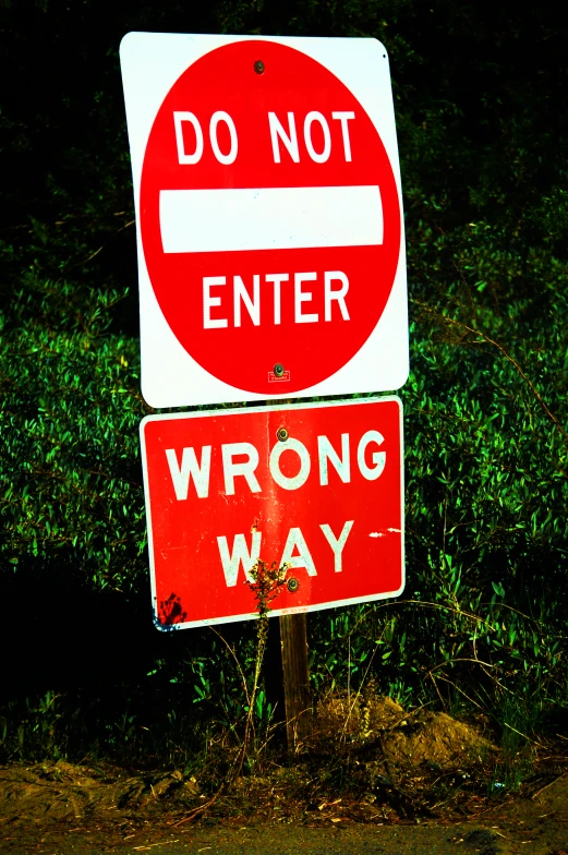 a red and white do not enter sign sitting on the side of a road