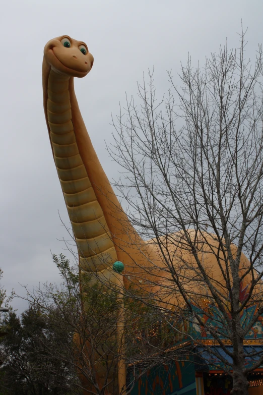 the very large snake statue is next to a tree