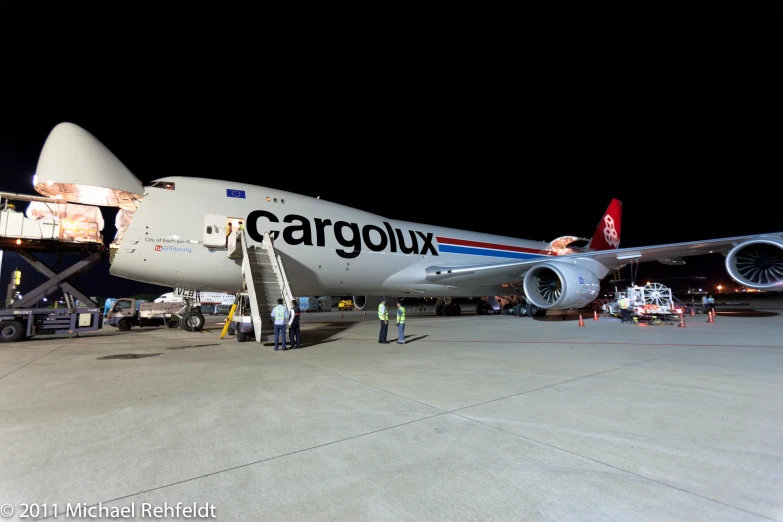 people standing around an airplane with cargo on the side