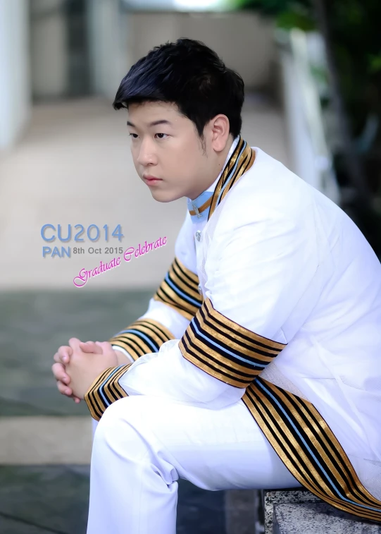 a male asian dressed in white sitting on a wall