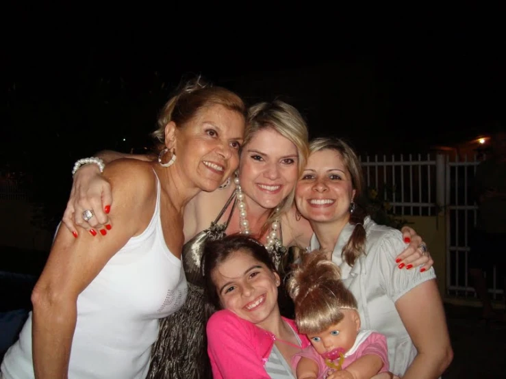 four women smile and hug each other while the girl is holding the baby