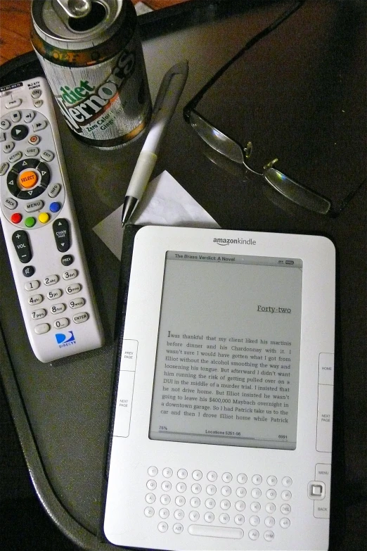 a table with a book, remote and a can of soda