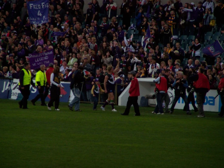 a large crowd is watching and walking through the grass