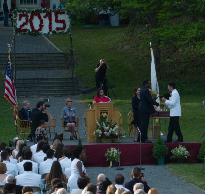 people are watching the speakers at an outdoor ceremony