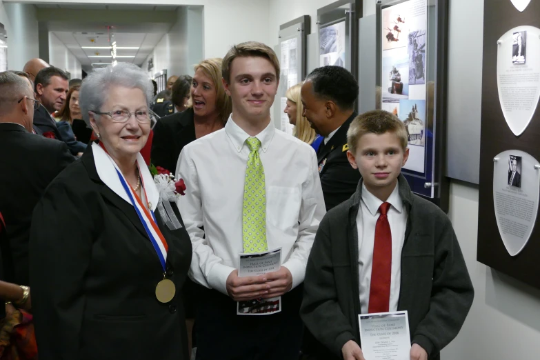 a woman standing between two boys holding an award