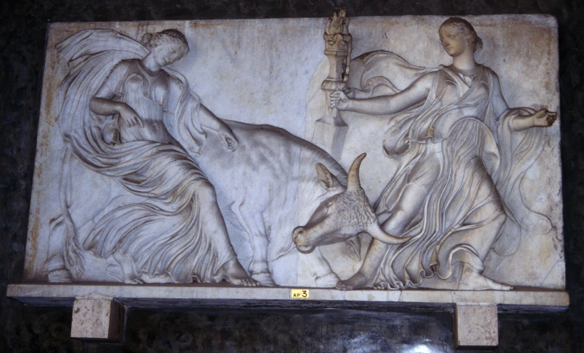 a carving of women standing next to a bull