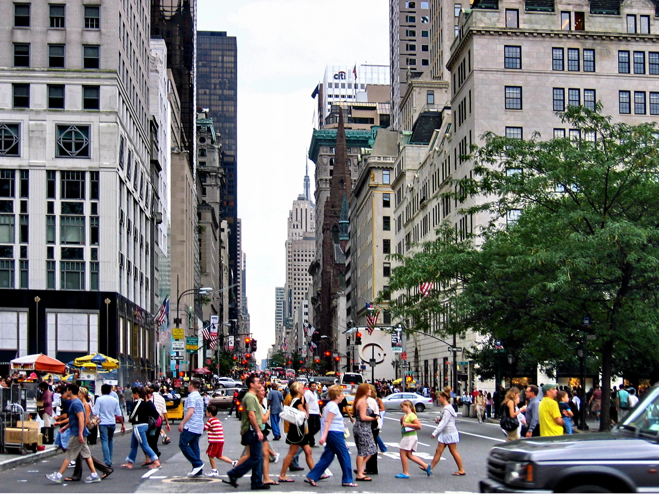 people walking across the street while a car is passing by