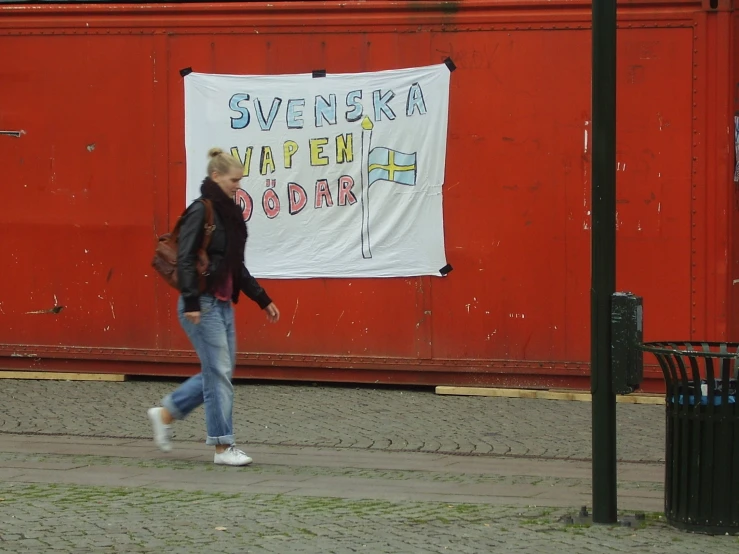 a woman walks past a protest sign, while carrying a bag