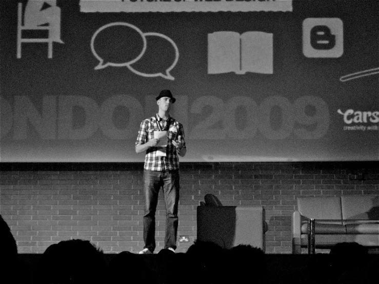 the young man is standing on a stage talking