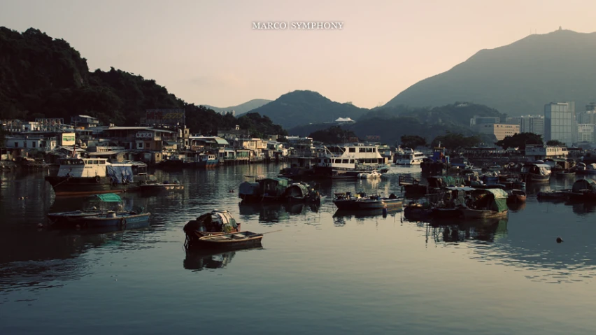 several boats are docked at the shore near a mountain