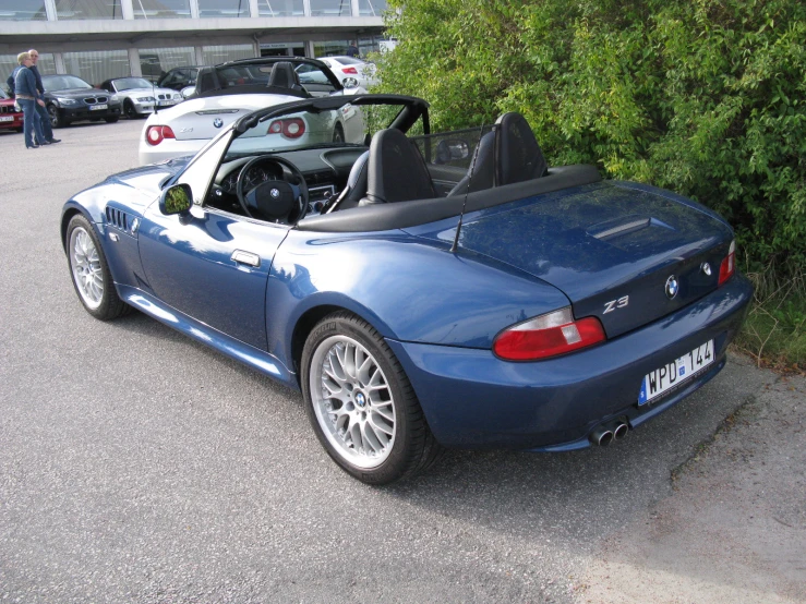 a blue sports car sits in the parking lot with other cars