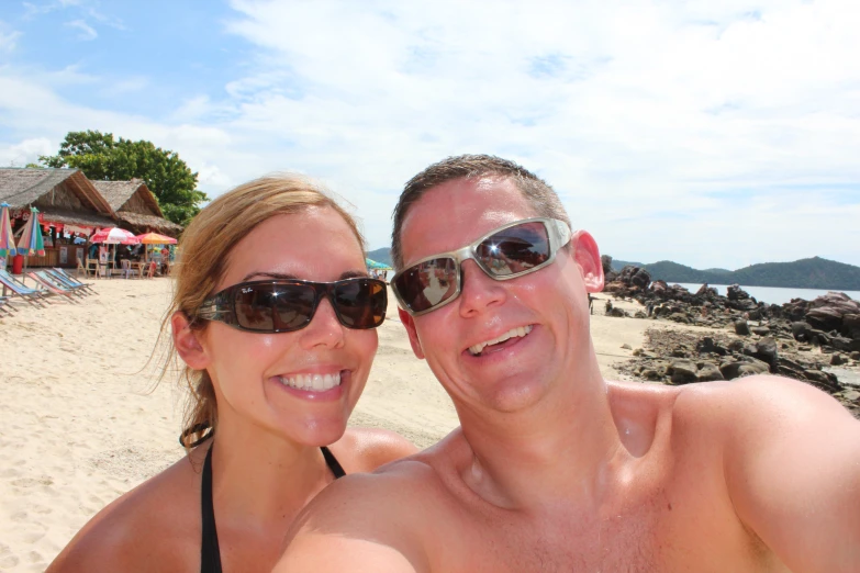 a man and woman posing together at the beach