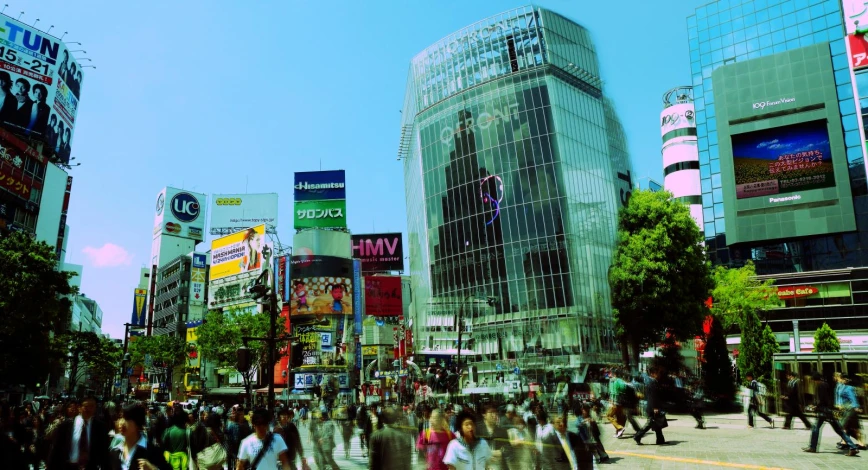 many people are walking down the street with large glass buildings