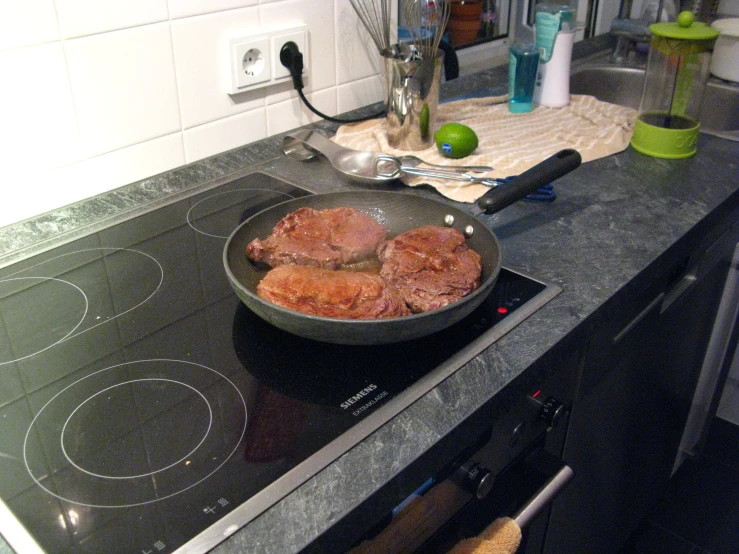 a pan of meat cooking on the stove top