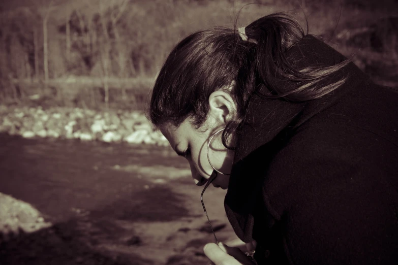 a woman is standing in the woods looking down at her cell phone