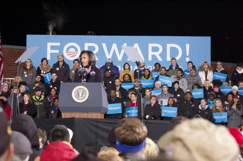 a crowd of people standing around a podium with signs