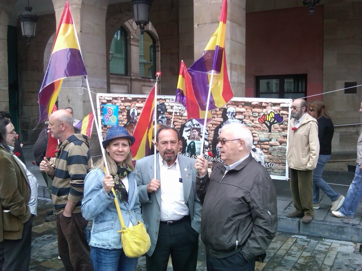 two men and one woman are smiling while holding flags