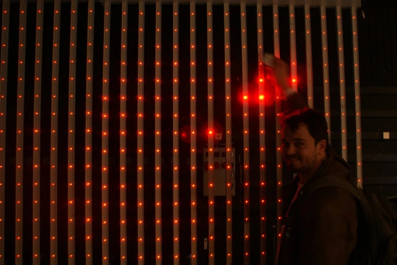 a man is standing next to a wall with red lights