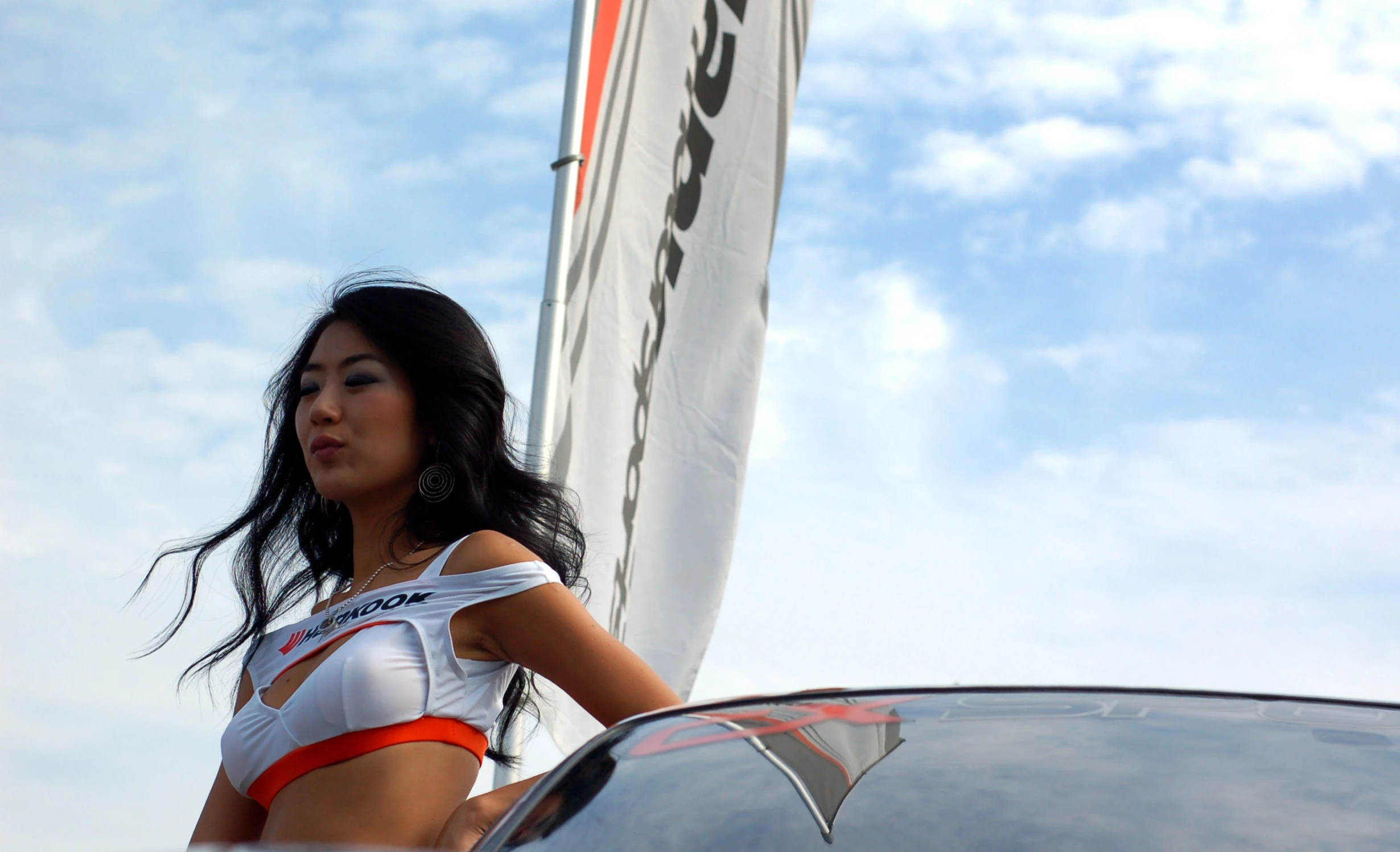 a beautiful woman in a white bikini standing next to a race car