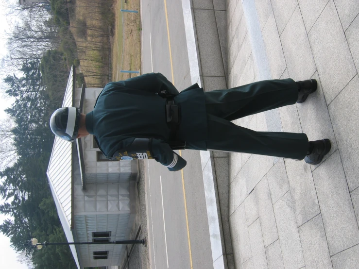 a man in a uniform that is standing on a sidewalk