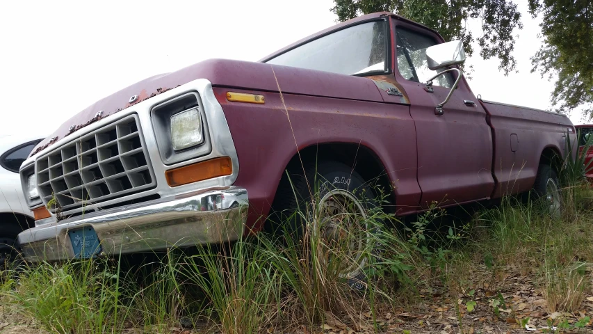 old purple truck parked next to a wooden fence