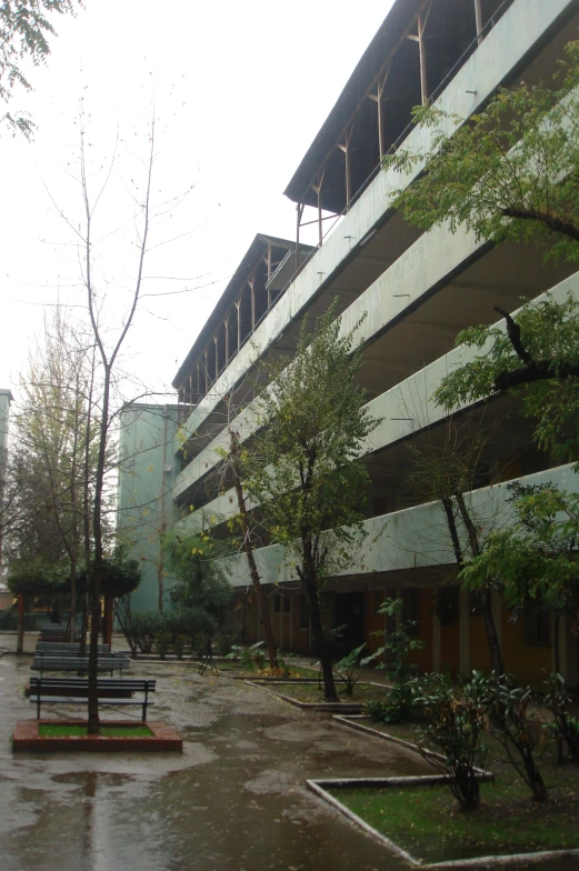 a rain soaked area near two buildings and benches