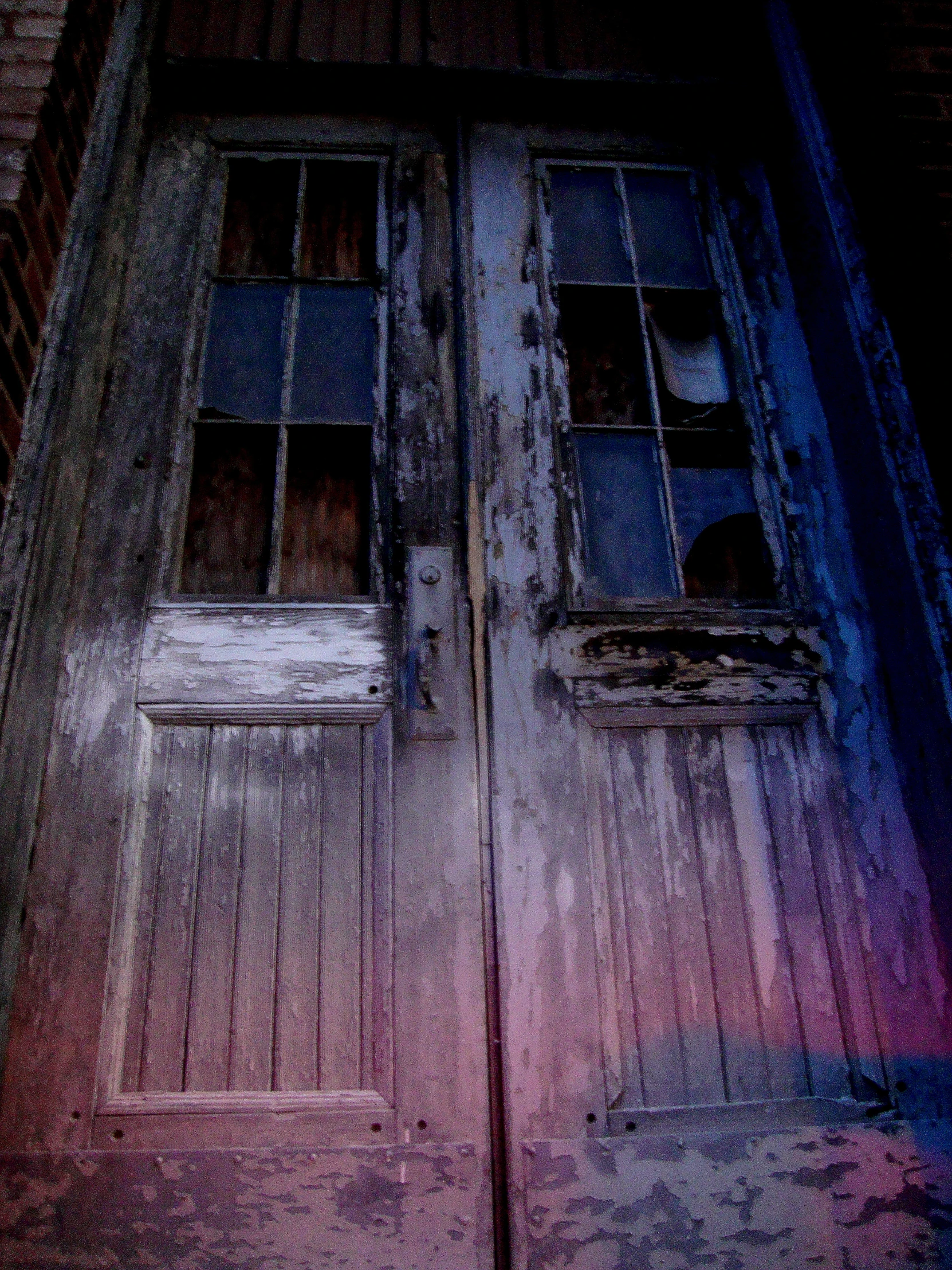 an old looking door in the dark with two windows