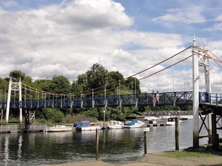 a bridge over water next to trees and boats