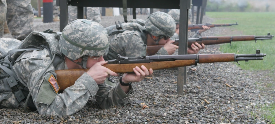 an army soldier in camouflage aiming his rifle