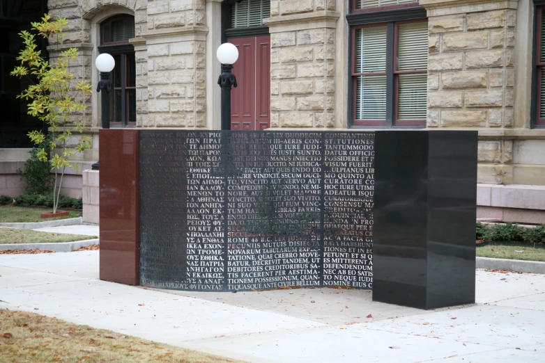 a black monument outside an old building in front of it