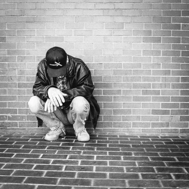 a man sitting on top of a brick floor in front of a wall