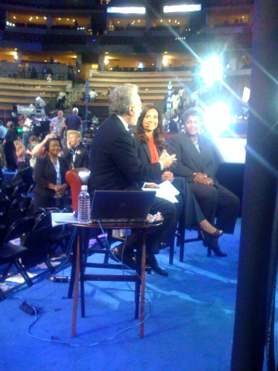 people are seated in chairs around a man at a desk