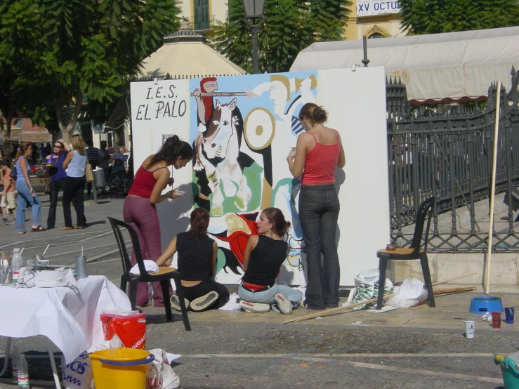 a woman is painting a mural with friends