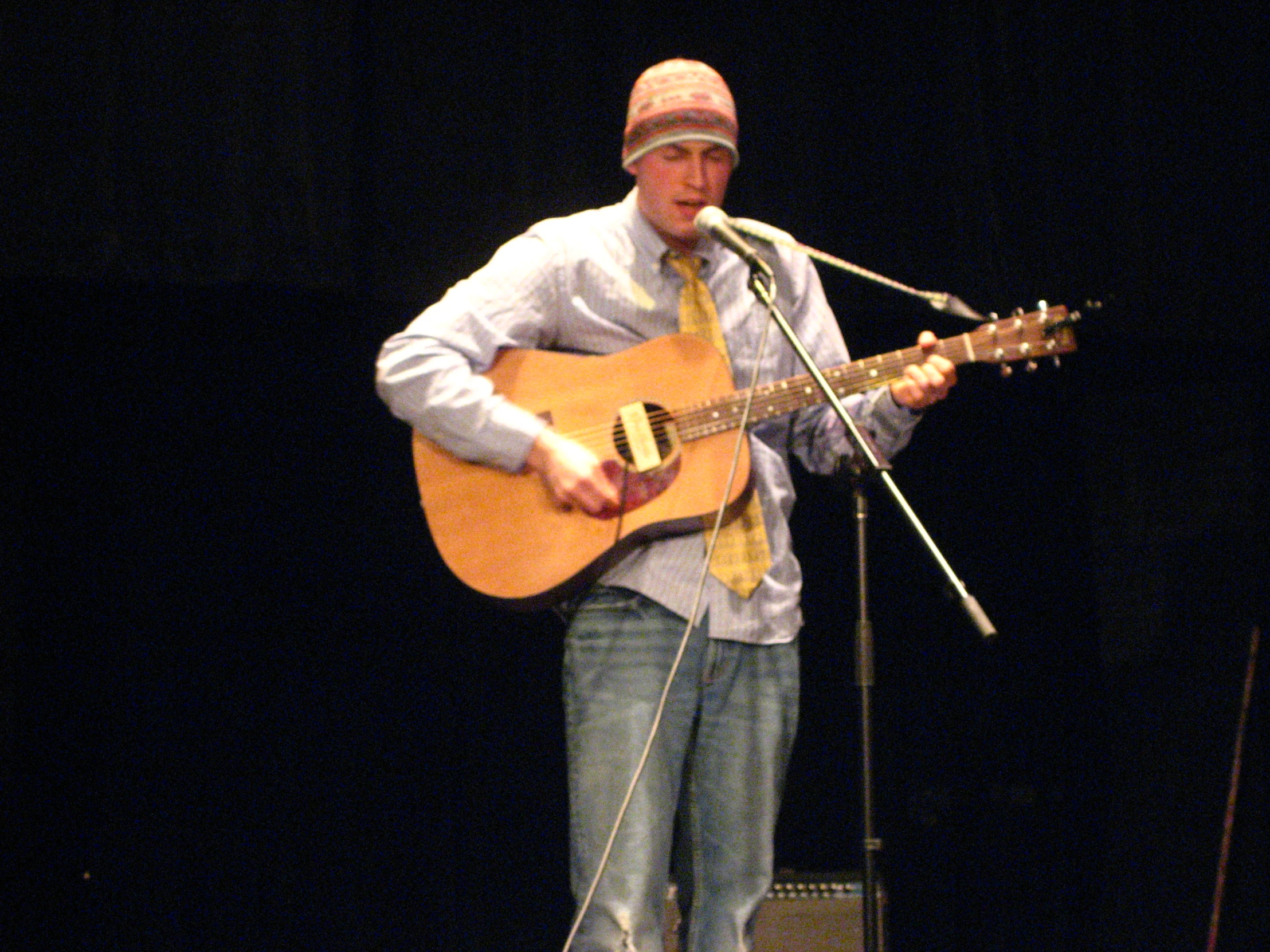 a man standing on stage while holding a guitar