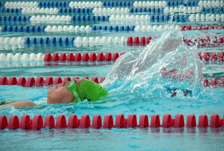 swimmers in a pool, competing and throwing their caps in the water