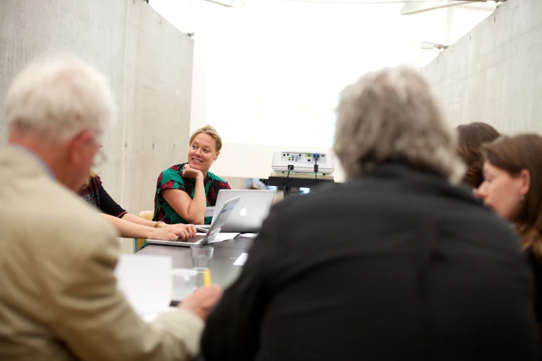 a group of people working at a table with laptops