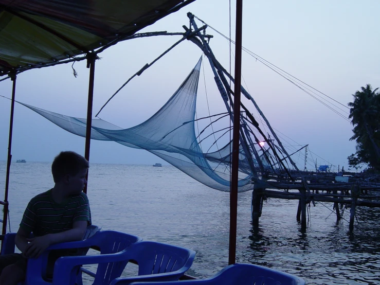 a boy sits on the front of his boat watching the sun rise