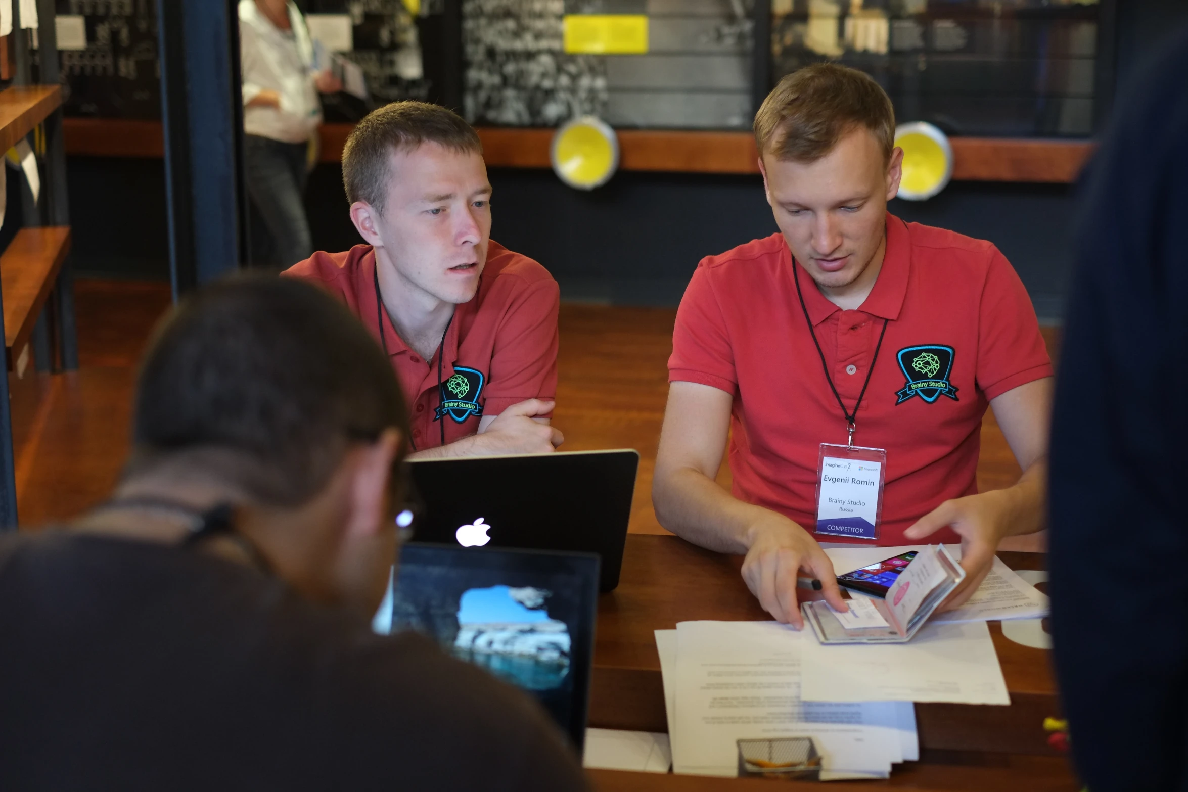 three men are sitting at a table working on a laptop