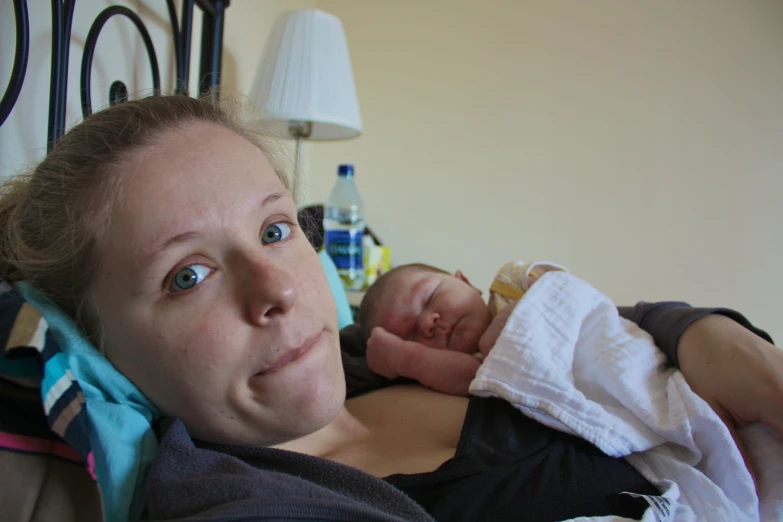 a woman with baby in her arms on the bed