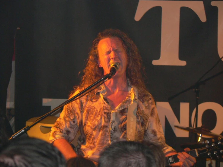 a man with long hair is singing into a microphone