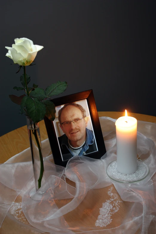 a rose and picture frame sitting on a table